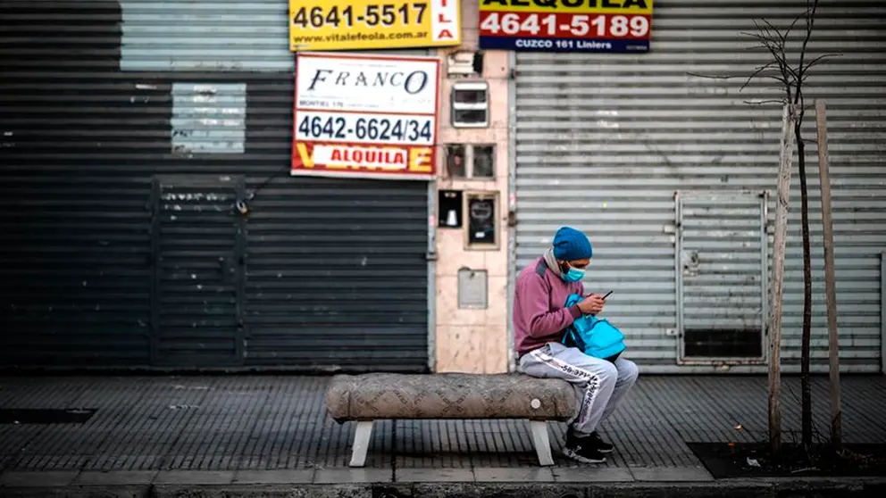 Un hombre revisa su celular frente a locales comerciales cerrados, en Buenos Aires, Argentina.&nbsp; EFE&nbsp;