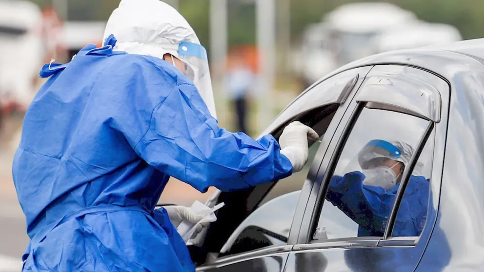 Personal de salud realizandon prueba de PCR a una persona en su motorizado. EFE