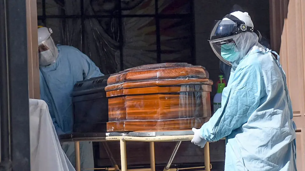 Personal forense levanta el féretro de una persona que murió por COVID-19 en Cochabamba. DICO SOLÍS.