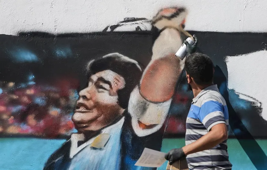 Un hombre pinta un mural con la imagen del exfutbolista argentino Diego Armando Maradona. EFE