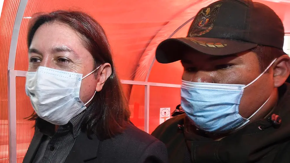 Marcel Rivas (i), ex director de Migración, es acompañado por un policía. APG