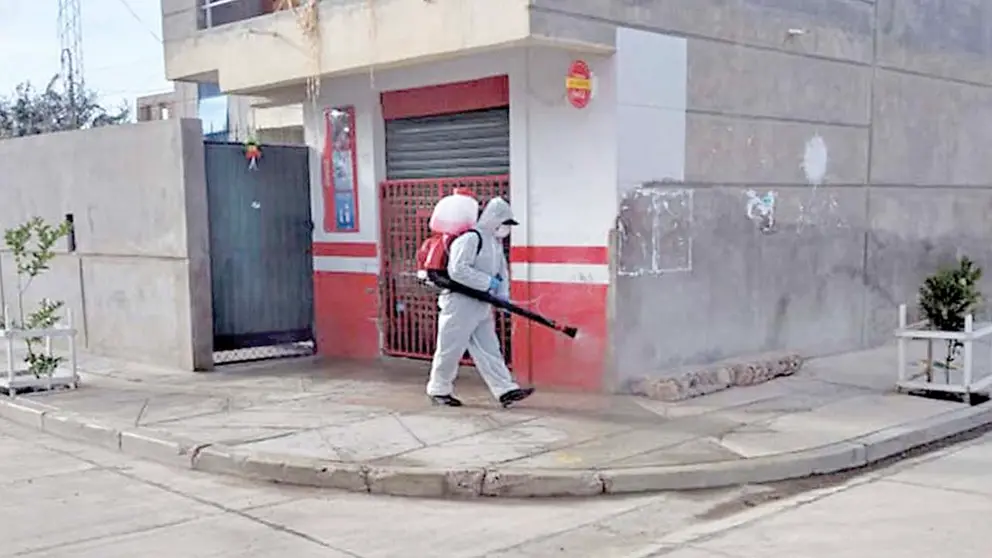 Un funcionario con traje de bioseguridad carga una mochila fumigadora para desinfectar calles de Colcapirhua. AlcaldÍa de Colcapirhua