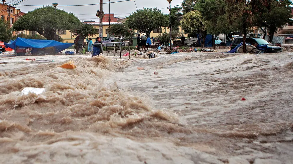 El agua en la calle y al fondo una mujer se sujeta de un tubo. CORREO DEL SUR