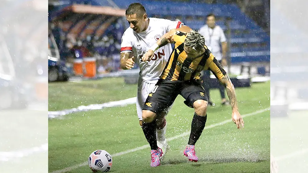 Esteban Orfano (i) de Royal Pari busca dominar la pelota ante la marca de su rival. ROYAL PARI