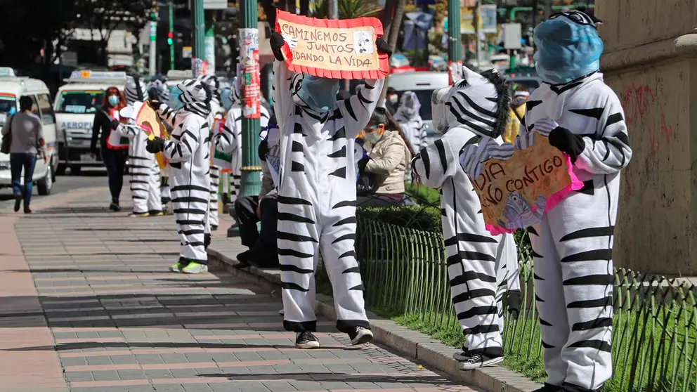 Las cebras, las educadoras viales, caminan por una calle con carteles de apoyo emocional a la población, en La Paz. EFE