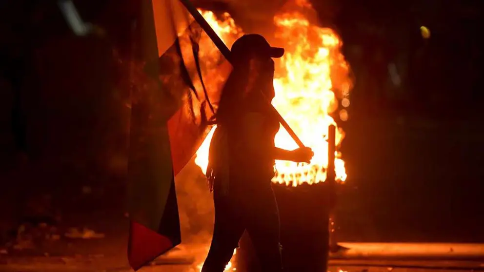 Una mujer camina con una bandera de Colombia durante una velat&oacute;n en homenaje al joven Nicol&aacute;s Guerrero, asesinado durante los enfrentamientos con miembros del Escuadr&oacute;n M&oacute;vil Antidisturbios (ESMAD), hoy en Cali (Colombia). EFE
