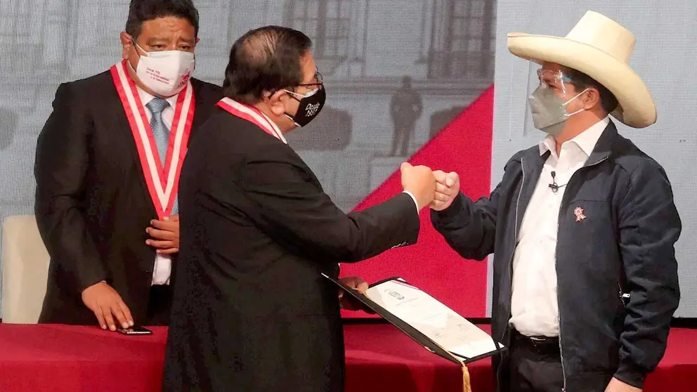 El presidente electo peruano Pedro Castillo (d) choca su puño con el presidente del JNE, José Luis Salas, que le entrega las credenciales de su nuevo cargo hoy, en Lima (Perú). EFE