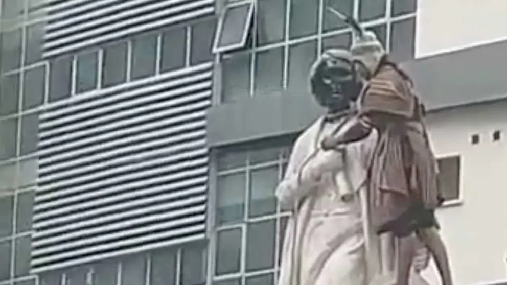 Captura de video en la que se ve a una joven atando una soga en la estatua. John Arandia