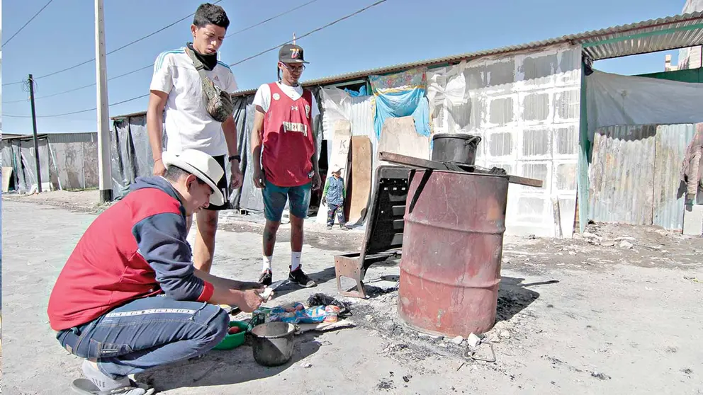 Venezolanos preparan sus alimentos en el sector de Colchane. APG