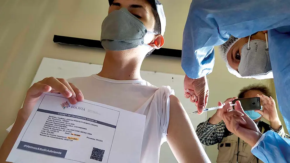 Un menor recibe una vacuna contra el coronavirus mientras muestra su carnet. DICO SOLÍS 