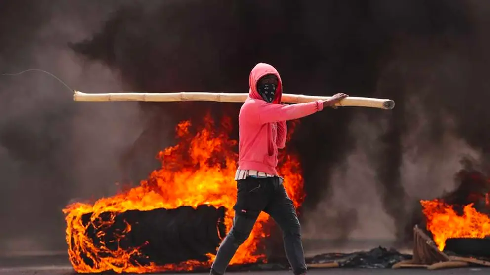 Un hombre camina junto a un neumático gigante en llamas durante una jornada de protestas en Haití, en una fotografía de archivo. EFE