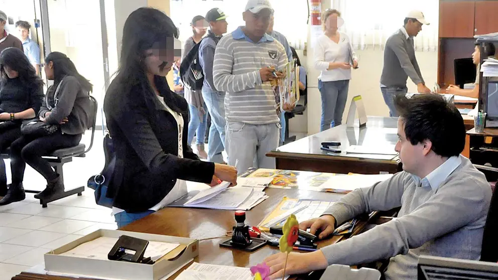 Una mujer entre varias personas que acuden a la Dirección de Trabajo para realizar diversos trámites. ARCHIVO