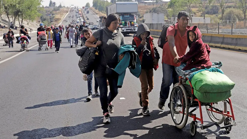 Una familia de migrantes camina por el municipio de San Martín Texmelucan, en la autopista Puebla-México. EFE