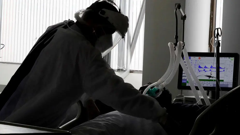 Una empleada de la salud atiende a un paciente en una unidad de cuidados intensivos para enfermos de COVID-19 en el Hospital El Tunal en Bogotá.       FUENTE- EFE