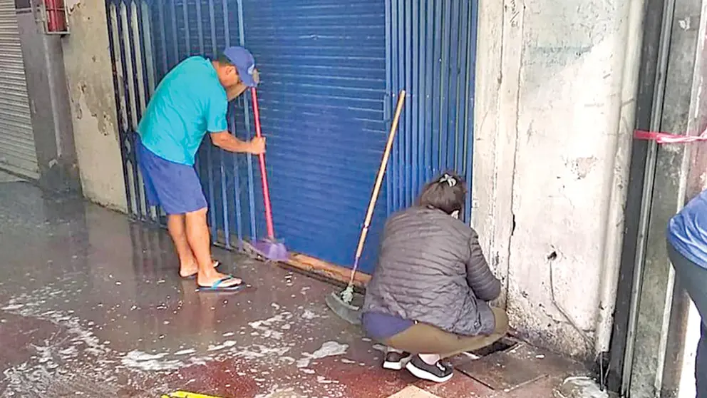 Comerciantes limpian la acera de su negocio, en el mercado 25 de Mayo. INTENDENCIA