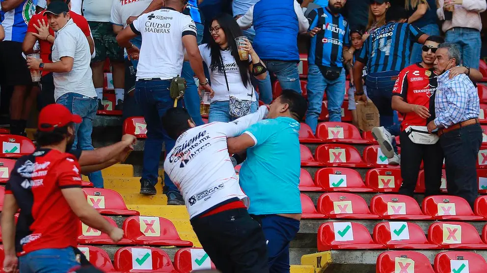 Aficionados de Quer&eacute;taro y Atlas se enfrentan al minuto 62, donde familias tuvieron que ser resguardadas en la cancha, durante un juego correspondiente a la jornada 9 del Torneo Clausura 2022 de la Liga MX del f&uacute;tbol mexicano en el estadio Corregidora de la ciudad de Quer&eacute;taro (M&eacute;xico). EFE/Enrique Contla
