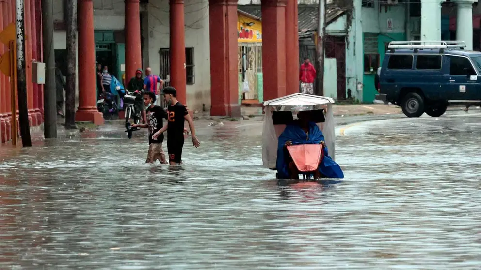 Varias personas caminan por una calle llena de agua, hoy en La Habana (Cuba). EFE