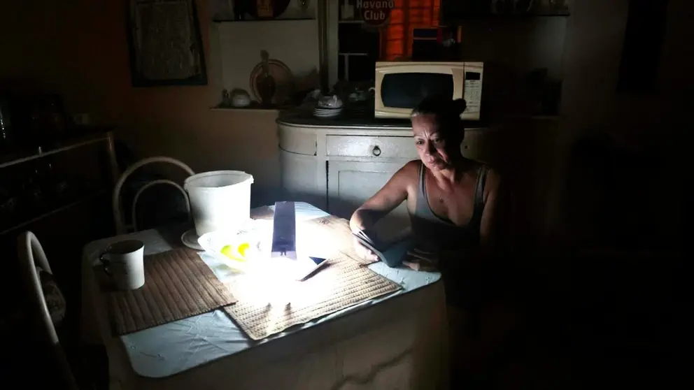 Una mujer revisa unas notas con la luz de una l&aacute;mpara durante un apag&oacute;n, el 18 de agosto de 2022, en La Habana (Cuba). EFE