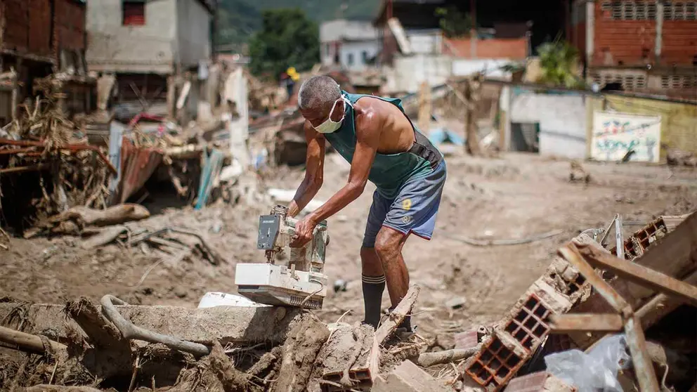 Personas buscan objetos para rescatar entre los escombros tras derrumbes provocados por las fuertes lluvias, hoy, en Las Tejer&iacute;as (Venezuela). EFE