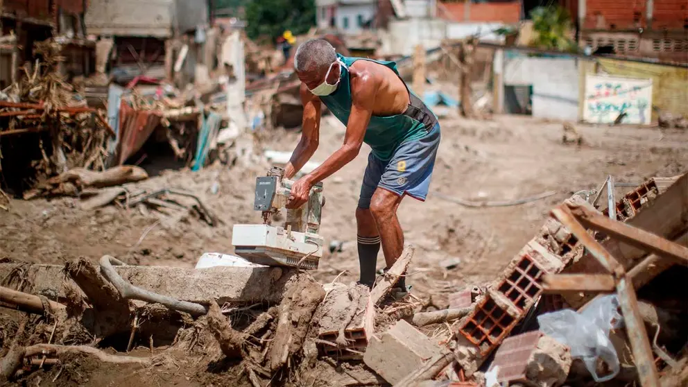 Personas buscan objetos para rescatar entre los escombros tras derrumbes provocados por las fuertes lluvias en Las Tejer&iacute;as (Venezuela). EFE