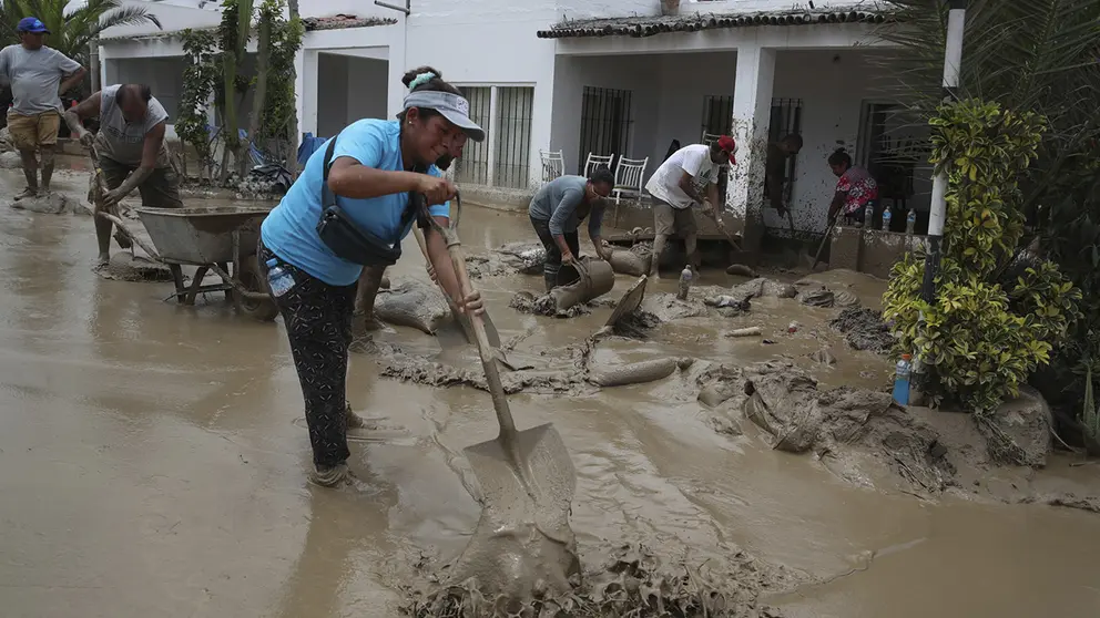 Personas ayudan a remover el lodo en una calle afectada por las lluvias, en el balneario de Punta Hermosa al sur de Lima (Per&uacute;), en una fotograf&iacute;a de archivo./ EFE