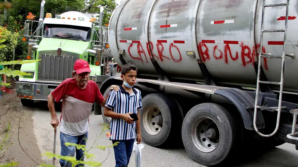 Dos personas caminan hoy, al lado de un cami&oacute;n con la frase carro bomba hoy, en la Vereda Santa Rosa, en Catatumbo (Colombia)./ EFE