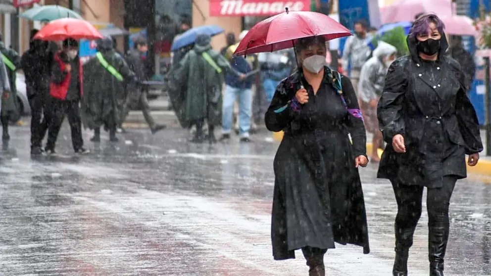 Un grupo de personas camina por las calles de Cochabamba, protegi&eacute;ndose de la lluvia con paraguas./ ARCHIVO