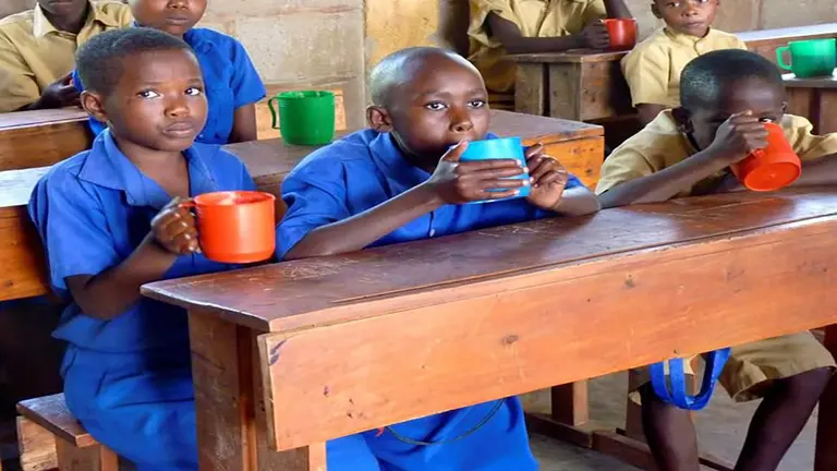 Unos ni&ntilde;os reciben una taza con comida en un campamento de refugiados en el norte de Ruanda. EFE