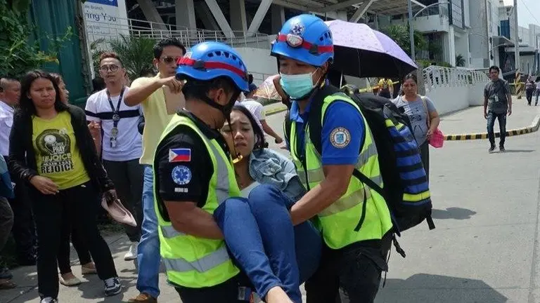 Una mujer es socorrida por rescatistas luego del terremoto en Filipinas. EFE