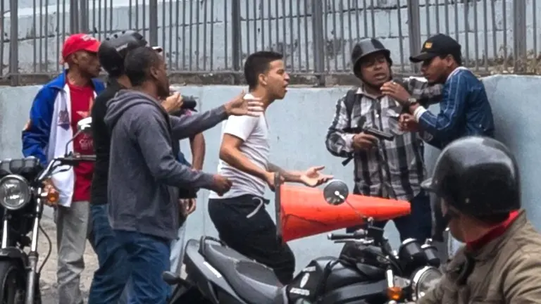 Un grupo de hombres, uno de ellos con un arma, se enfrenta en las inmediaciones del Palacio Federal Legislativo. EFE