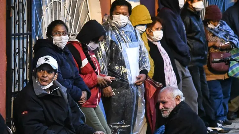 Un grupo de personas de la tercera edad haciendo fila en la madrugada en una entidad financiera, en Cochabamba. NO&Eacute; PORTUGAL