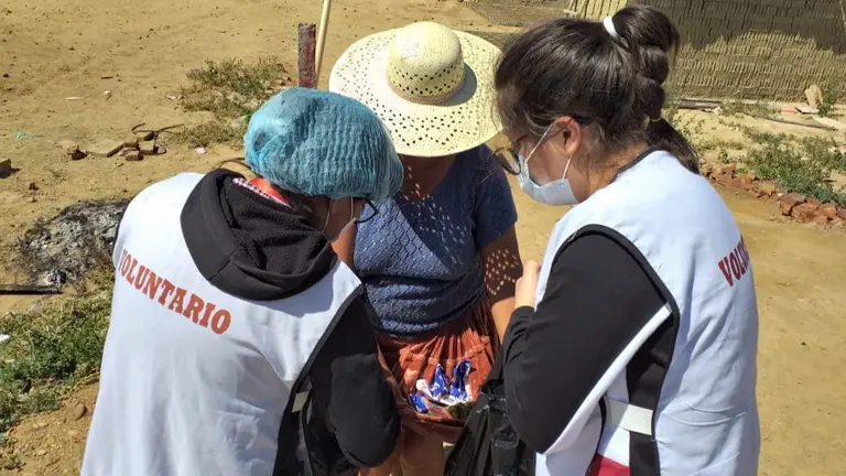 Dos voluntarias entregan productos a una vecina en Cercado.