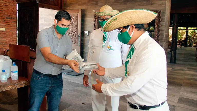 Empleados de un restaurante que reabre sus puertas se reparten elementos de bioseguridad para atender clientes en Santa Cruz. EFE