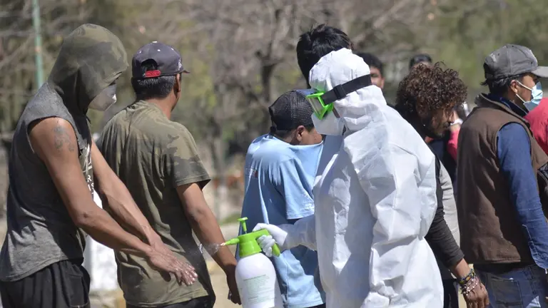 Un encargado del rastrillaje roc&iacute;a las manos de una persona en situaci&oacute;n de calle con alcohol. NO&Eacute; PORTUGAL