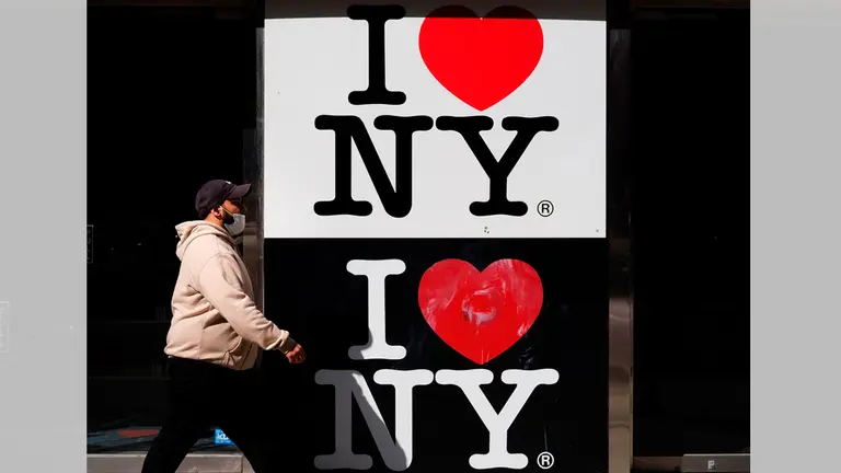 Un transeunte fue registrado este martes al pasar frente un almacen cerrado, en la zona comomercial de Times Square, en Nueva York. EFE