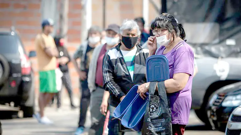 Un grupo de personas con barbijos esperan alimentos en un comedor comunitario en Buenos Aires, Argentina. EFE 