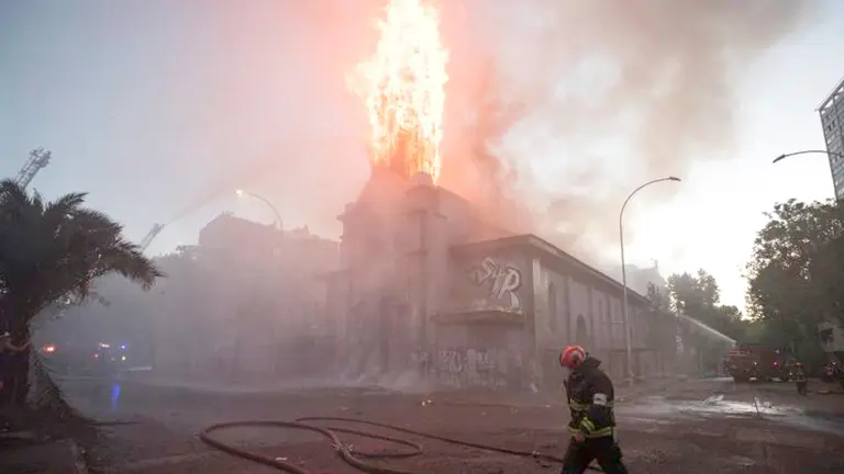 Un grupo de bomberos trabaja en la extinción del incendio de la parroquia de la Asunción este viernes en los alrededores de la Plaza Italia de Santiago (Chile). EFE