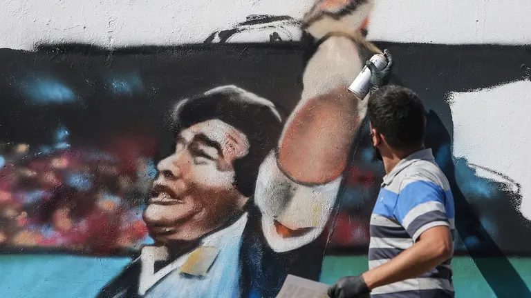 Un hombre pinta un mural con la imagen del exfutbolista argentino Diego Armando Maradona. EFE