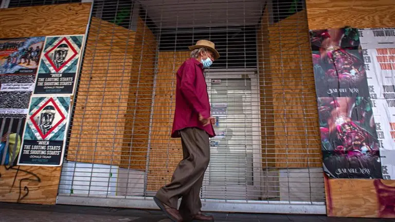 Un hombre pasea en Estados Unidos con afiches que impulsaron el voto. EFE