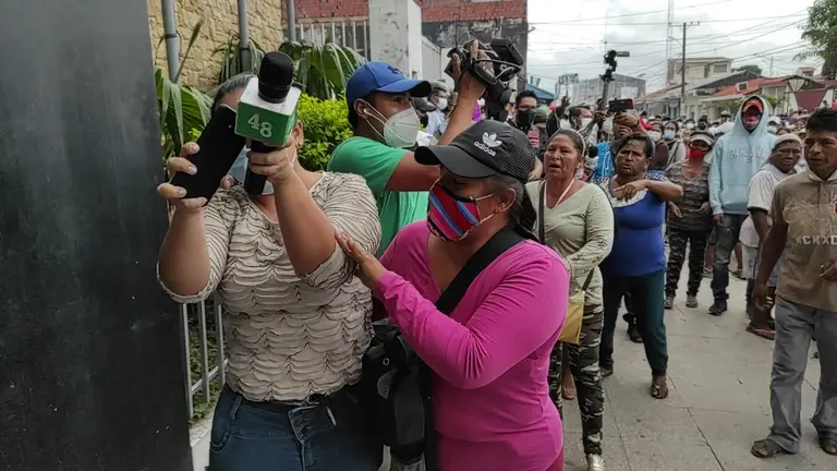 La periodista de Canal 48 de la ciudad de Montero, Vivian P&eacute;rez, trata de protegerse del ataque de padres de familia que reclamaban un bono escolar en especie. Diario Zona Norte de Montero