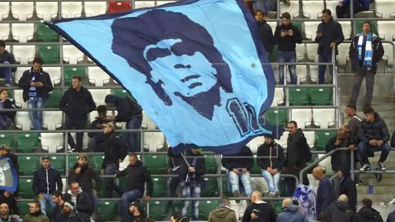 Aficionados del Nápoles muestran una bandera con la imagen del exjugador napolitano Diego Armando Maradona, durante un partido de su equipo. EFE-Archivo