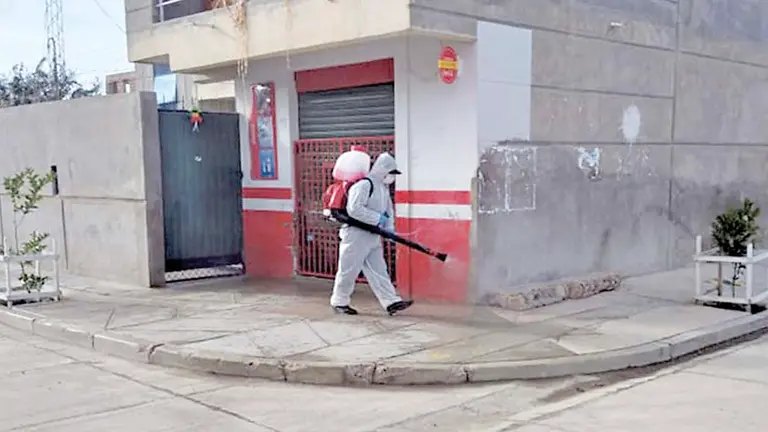 Un funcionario con traje de bioseguridad carga una mochila fumigadora para desinfectar calles de Colcapirhua. AlcaldÍa de Colcapirhua
