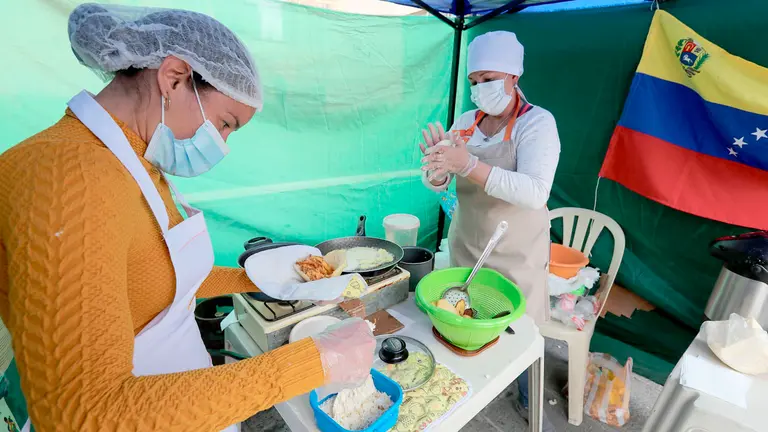 Venezolanas, que decidieron quedarse en el país, preparan arepas en su puesto parte de una feria ambulante en el centro de La Paz. EFE