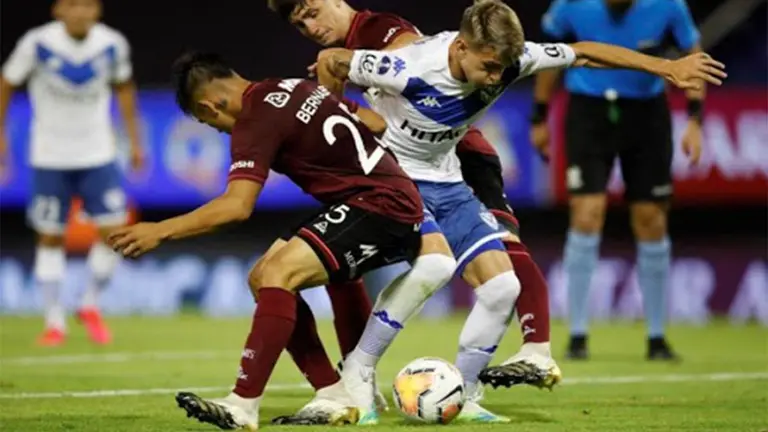 Lucas Orellano (c) de V&eacute;lez disputa un bal&oacute;n ante Alexander Bernabei (i) de Lan&uacute;s. ARCHIVO EFE