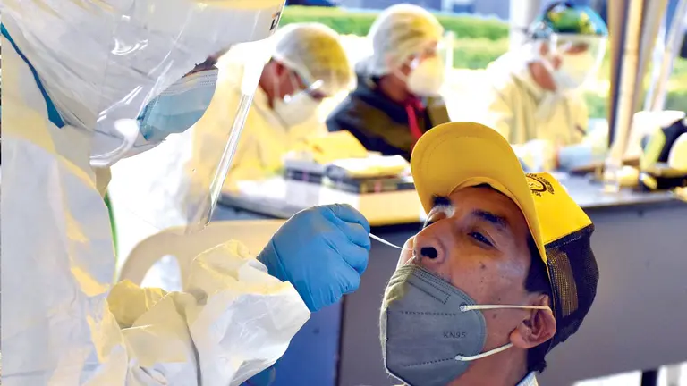 Un hombre es hisopado por un funcionarios de salud. DICO SOLÍS