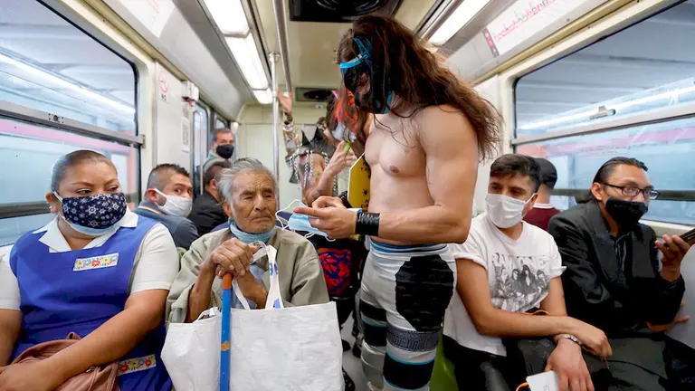 Profesionales de la lucha libre mexicana viajan concienciando del uso del tapabocas y regalándolos, en el metro de Ciudad de México (México). EFE