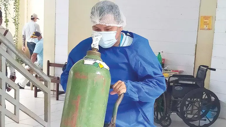 Un trabajador traslada un tanque de oxígeno en Trinidad. APG