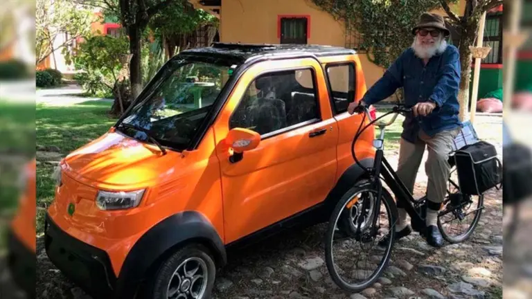 Una persona con una bicicleta el&eacute;ctrica junto a un veh&iacute;culo de Quantum Motors. Quantum Motors Facebook.