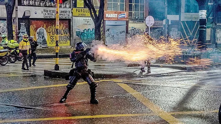 Un policía disparando gas lacrimógeno en Bogotá.FEDERICO RÍOS-THE NEW YORK TIMES