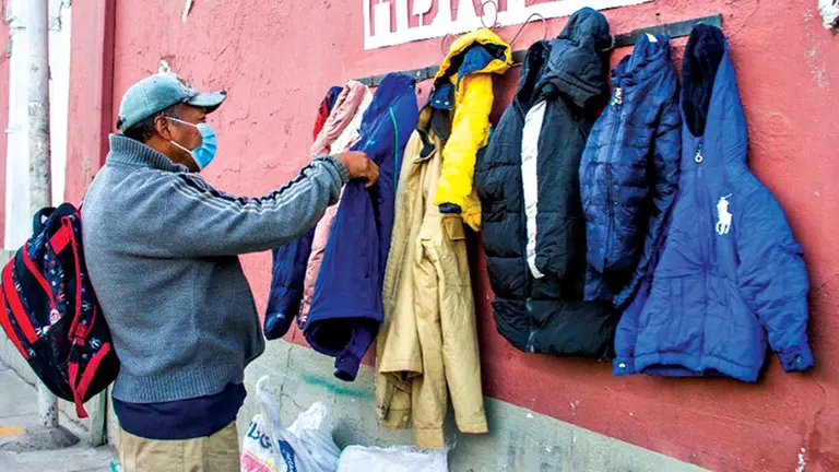 Un ciudadano dona prendas en el perchero invernal. GAMC